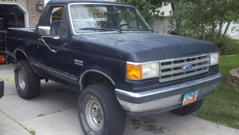 Black Ford Bronco parked in a driveway. Has a removable top