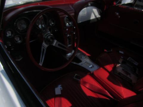 1964 Ford Ranchero - The interior of a 1964 Chevrolet Corvette features a red steering wheel and matching seats.