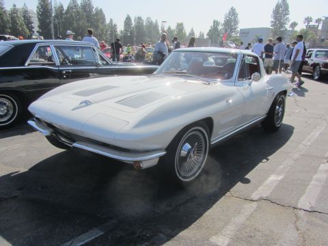 1964 Ford Ranchero - A white 1963 Corvette Sting Ray coupe is parked next to a black coupe at an outdoor car show.