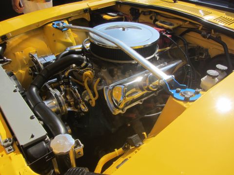 1964 Ford Ranchero - Close-up view of a modified V8 engine bay in a yellow vehicle, a chrome air cleaner and blue strut tower brace.
