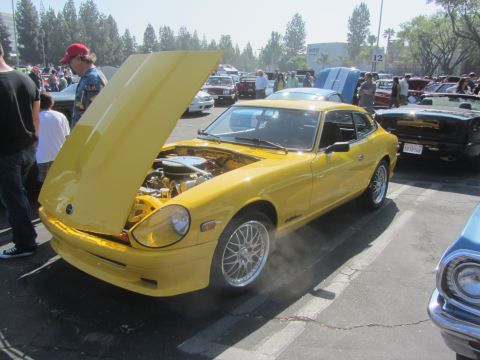 1964 Ford Ranchero - A yellow sports coupe is displayed with its hood open at an outdoor car show.
