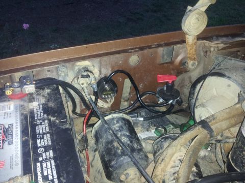 1988 Ford Bronco - Close-up view of the engine bay, showing the battery, various wires, and a red-handled switch.