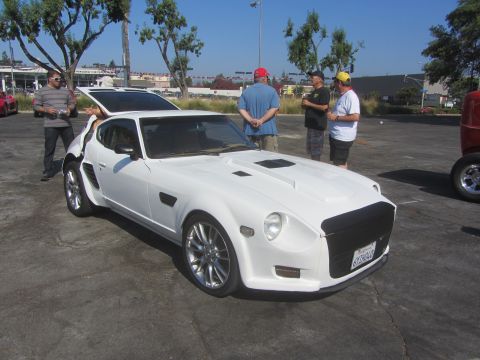 1964 Ford Ranchero - A white custom sports car is parked outdoors with people standing around it.