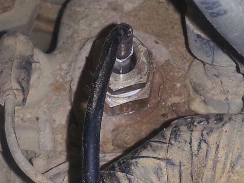 1988 Ford Bronco - A close-up view of a mechanical component, possibly a sensor or fitting, on a vehicle's undercarriage.