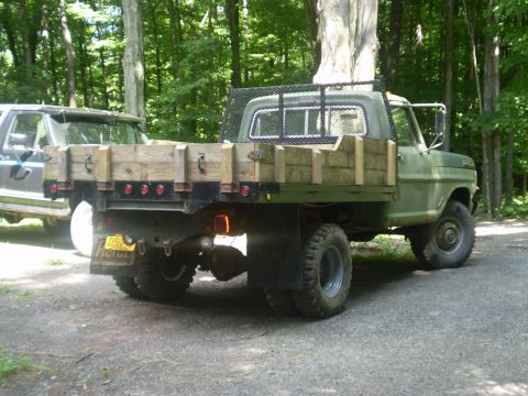 1979 Ford Bronco - This 1979 Ford F-250 flatbed truck features a custom wooden bed and is parked next to another vehicle in a wooded area.