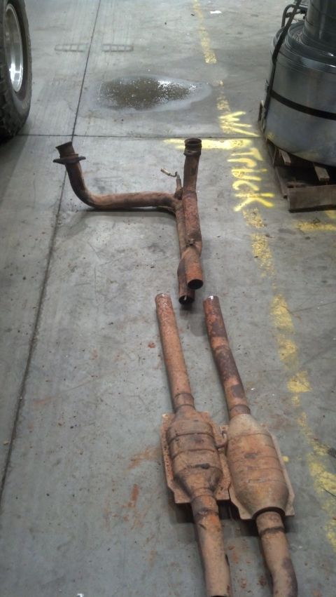 1993 Ford Bronco - Discarded exhaust system components lie on a workshop floor.