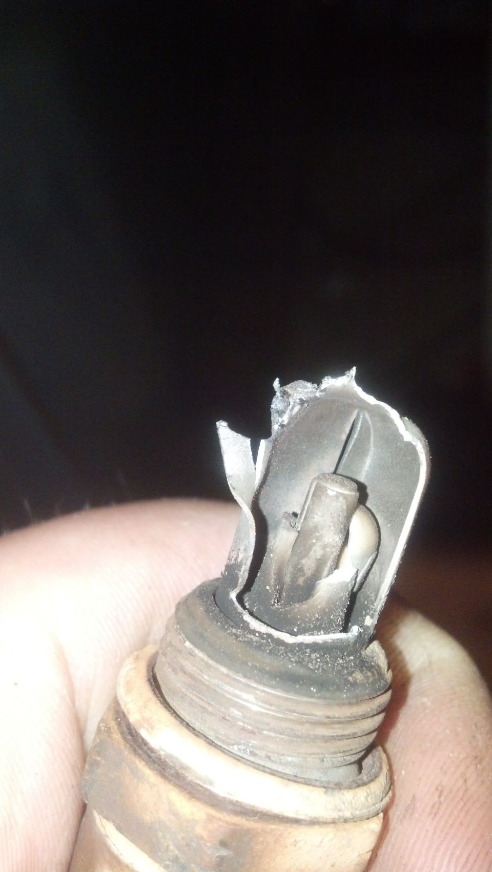 Damaged spark plug held in hand