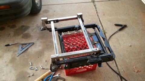 1991 Ford Festiva - A car seat frame is elevated on a milk crate, surrounded by tools and hardware.