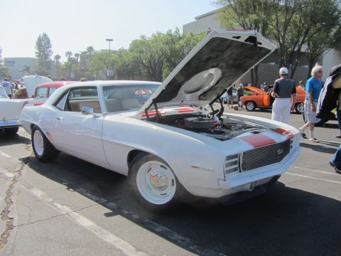 1964 Ford Ranchero - A white 1969 Chevrolet Camaro SS with its hood open is displayed at an outdoor car show.