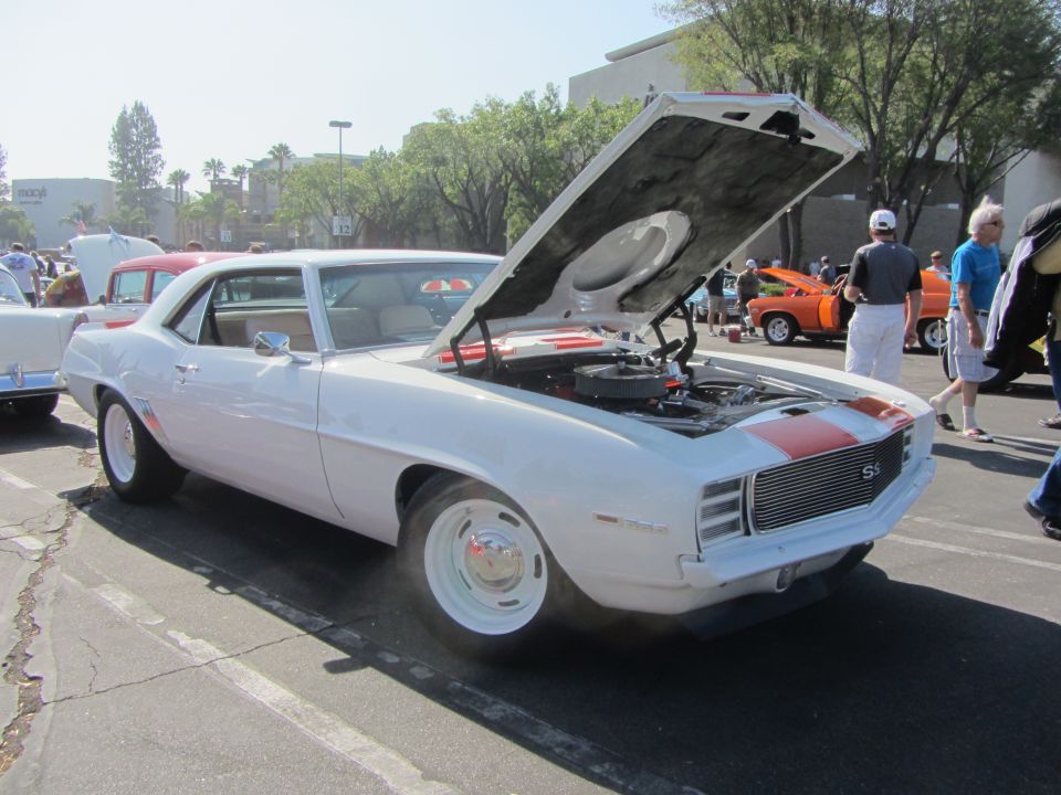 White 1969 Chevrolet Camaro SS coupe with orange stripes on hood and trunk, hood open, parked outdoors