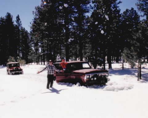 1979 Ford Bronco - A red 1979 Ford Bronco is stuck in the snow, with two people standing nearby. Another vehicle is visible in the background.