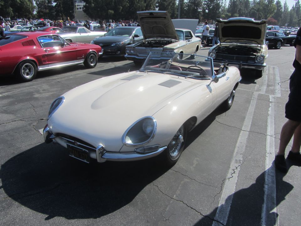 Cream-colored convertible sports car with chrome accents and wire wheels, parked on asphalt