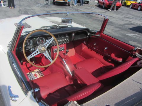1964 Ford Ranchero - The interior of a classic convertible features red upholstery and a distinctive steering wheel, with other vehicles visible in the backgrou…
