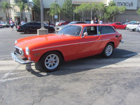1964 Ford Ranchero - An orange Volvo P1800 ES station wagon is parked in a lot with a Macy's store in the background.