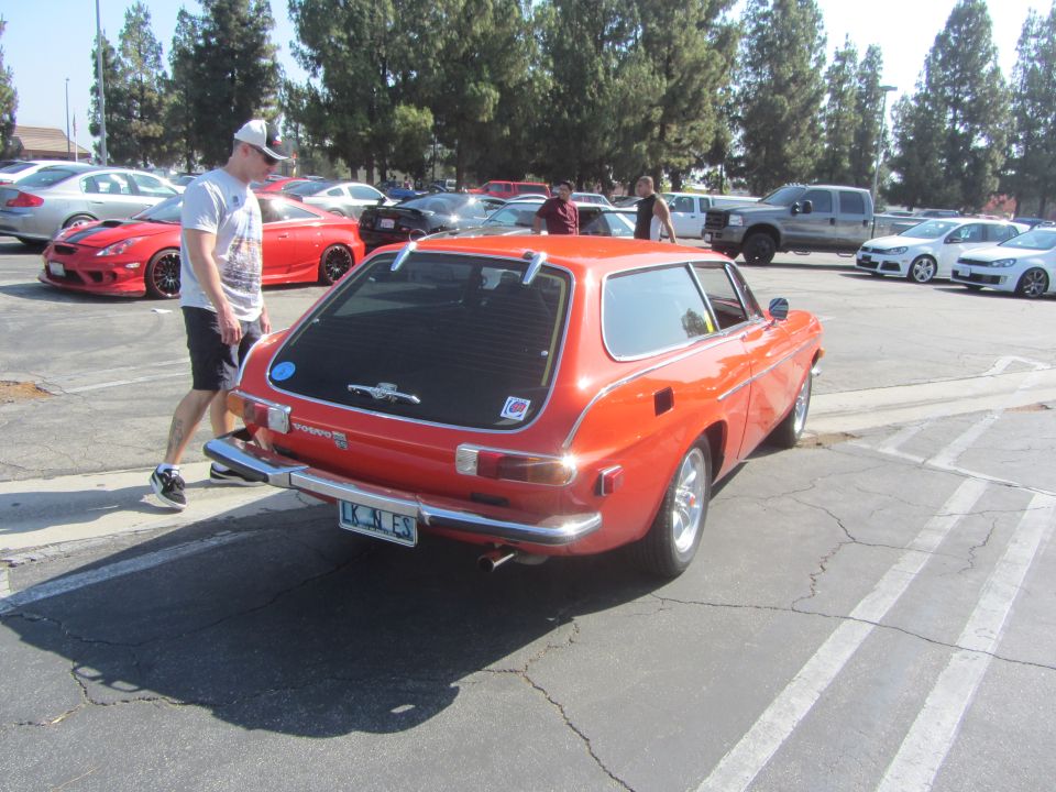 Orange Volvo P1800 ES wagon rear view with a person walking by
