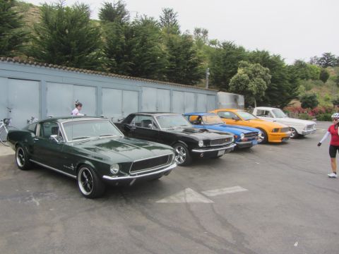 1964 Ford Ranchero - A row of classic American muscle cars are lined up in front of a garage.