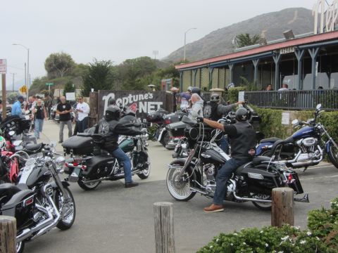 1964 Ford Ranchero - A group of motorcyclists are gathered outside Neptune's Net, a restaurant with a view of the ocean and hills.