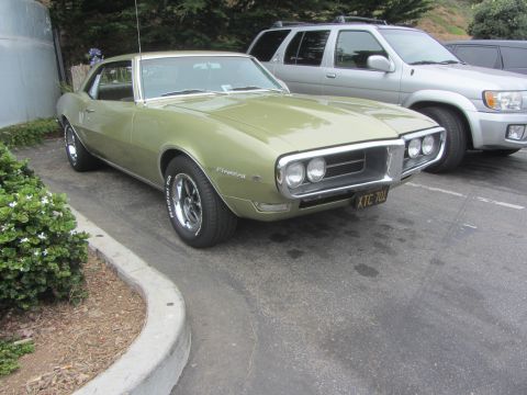 1964 Ford Ranchero - A light green 1968 Pontiac Firebird is parked next to a silver SUV, showing its distinctive front grille and chrome wheels.