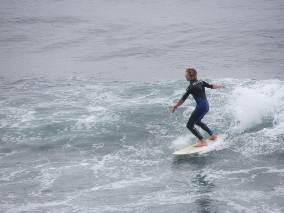 Surfer in a blue and black wetsuit rides a wave on a surfboard