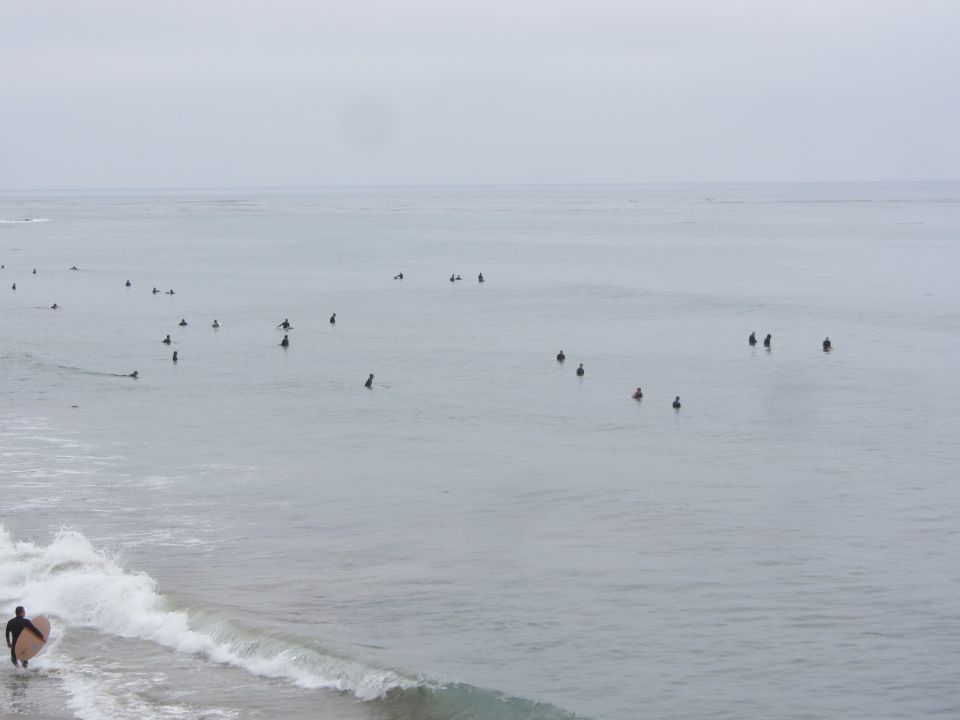 Surfers waiting for waves in the ocean under a cloudy sky