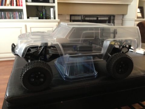 1986 Ford Bronco - Unpainted clear body for an RC truck sits on a dark surface, revealing its internal mechanics.