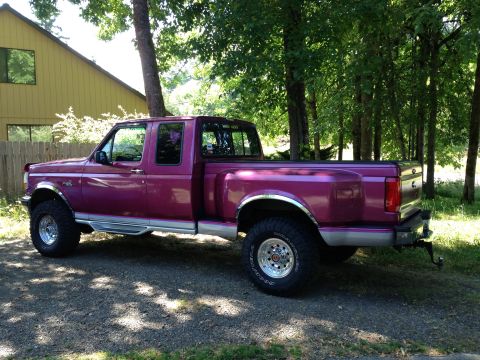 1992 Ford F-150 - Driver-side profile of a raspberry-magenta ninth-generation Ford F-Series extended-cab 4x4 pickup with a two-tone silver lower body stripe,…