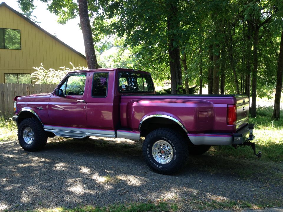 Magenta Ford F-150 extended cab 4x4 pickup, driver-side profile on gravel