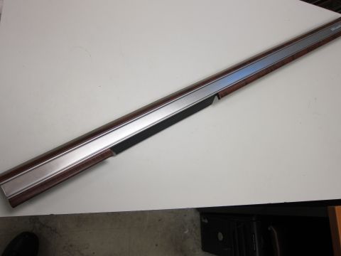 2001 Ford Crown Victoria - A close-up of a car's interior trim piece, wood grain and a metallic strip.