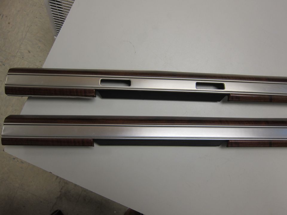 Two metal and wood-grain door trim pieces with rectangular cutouts
