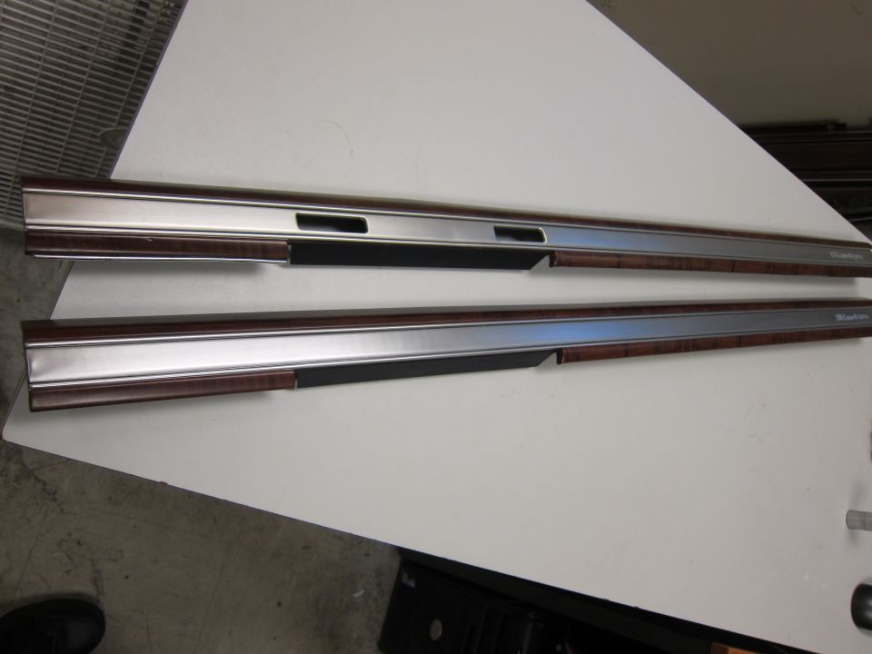 Two car door trim pieces with wood grain and chrome accents