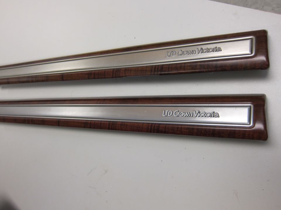 Two wood-grain and metal trim pieces with 'LTD Crown Victoria' text