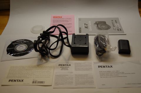 1983 Ferrari Enzo - Various accessories for the Pentax K-7 camera are laid out on a white surface.