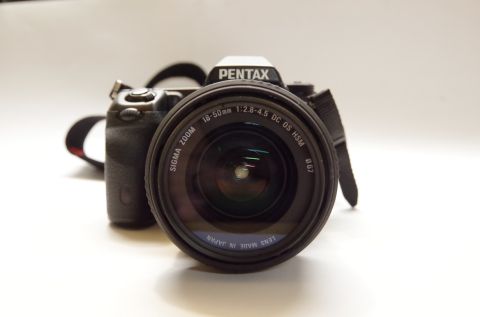 1983 Ferrari Enzo - A Pentax DSLR camera is shown with a Sigma zoom lens attached, displaying various technical specifications.