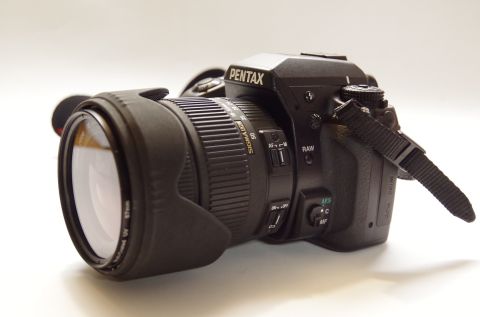 1983 Ferrari Enzo - A black Pentax digital camera with a Sigma zoom lens is displayed against a white background.