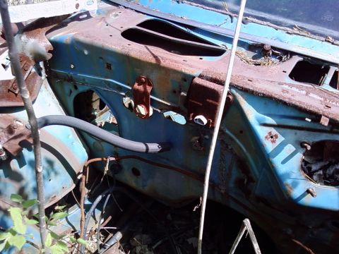 1974 Dodge Challenger - The engine bay of a heavily rusted blue vehicle shows significant decay and disarray.