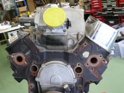 1976 Chevrolet Corvette - Engine block with intake manifold and yellow cap, chrome exhaust pipe visible.