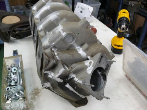 1976 Chevrolet Corvette - An intake manifold is shown on a workbench, alongside a yellow drill and a container of hardware.
