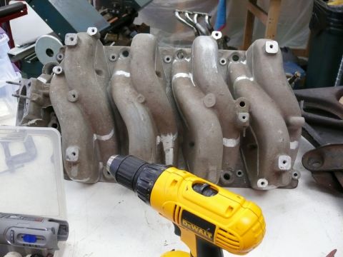 1976 Chevrolet Corvette - A close-up of an engine intake manifold with a yellow DeWalt drill positioned in front of it.