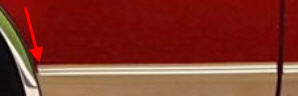1994 Ford Bronco - Tight crop of a red vehicle's lower body panel showing the gold and tan pinstripe body-side molding, with a red arrow graphic added to poin…