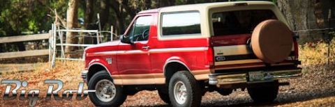 1994 Ford Bronco - Rear view of a red and tan Ford Bronco with a spare tire mounted on the tailgate.