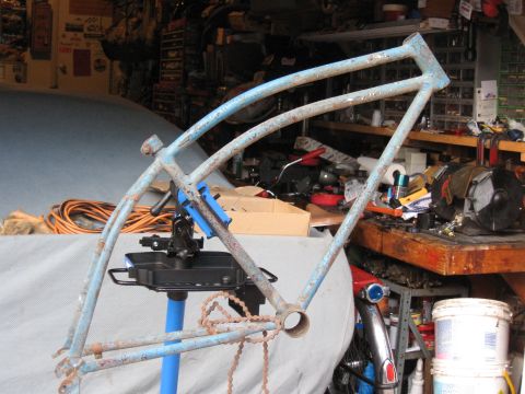 1994 Ford Bronco - A rusty blue bicycle frame is mounted on a repair stand in a workshop, surrounded by tools and supplies.