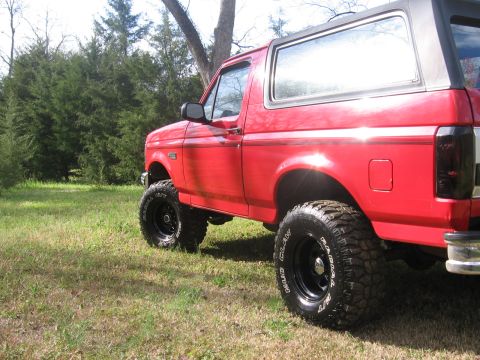 1992 Ford Bronco - This red 1992 Ford Bronco features a lifted suspension and aggressive off-road tires, giving it a stance.