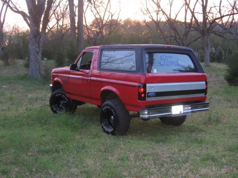 1992 Ford Bronco - Rear view of a red Ford Bronco with a black top and aftermarket wheels.