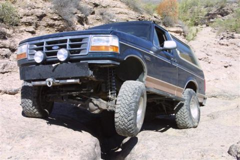 1994 Ford Bronco - This lifted Ford Bronco navigates rocky terrain, its suspension clearly visible.