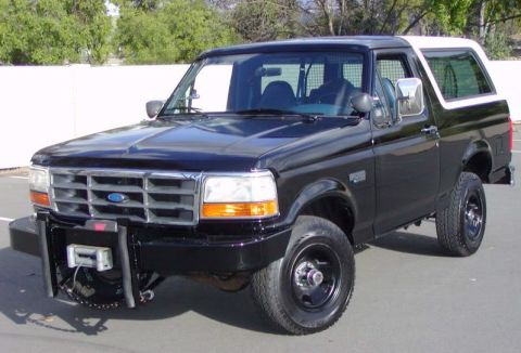 1992 Ford Bronco - This black Ford Bronco features a white removable top and an aftermarket front bumper with a winch.