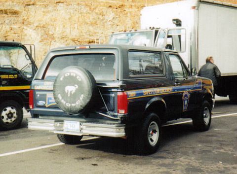 1992 Ford Bronco - 1992 Ford Bronco marked for DMV Safety Enforcement is parked next to a large truck.