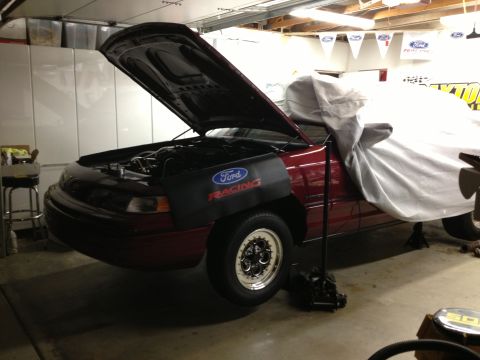 1992 Ford Crown Victoria - A red Ford Crown Victoria is parked in a garage with its hood up and a car cover on.