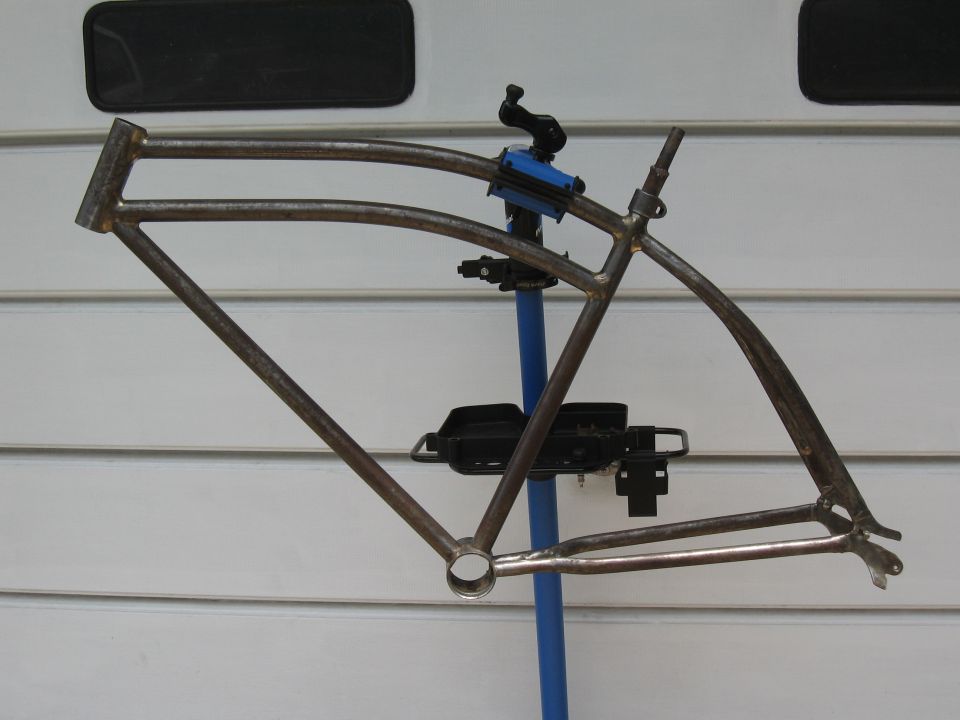 Rusty metal bicycle frame on a blue stand against a white wall