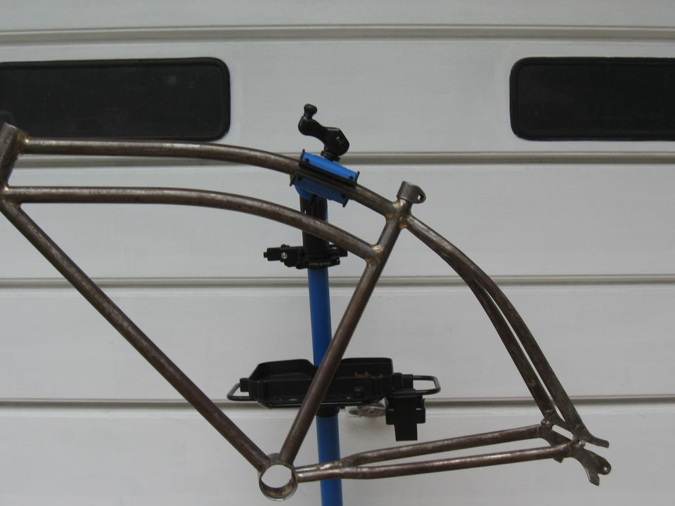 Bare bicycle frame on a stand against a white paneled background