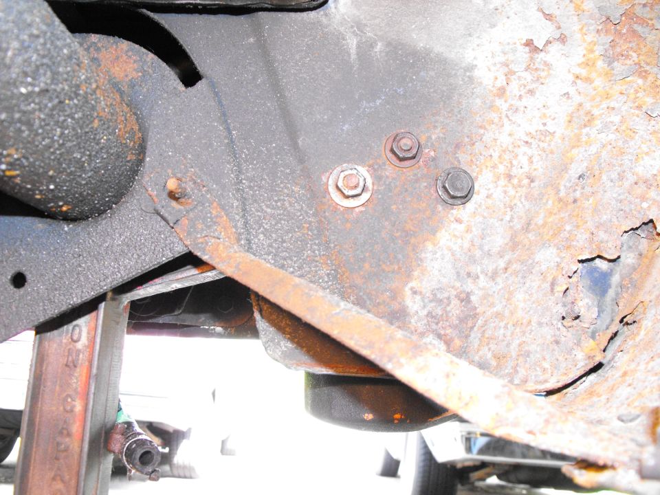 This shot shows the view from inside the front passenger's side wheelhouse (like you were the front of the tire). There's the three mounting bolts/nuts holding the filter housing, from the back. Hanging just below is the bottom of the filter.